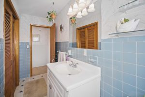 Bathroom with blue tile, a white sink and a large vanity mirror