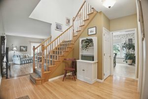 Bright foyer with a wooden staircase and views into adjoining rooms