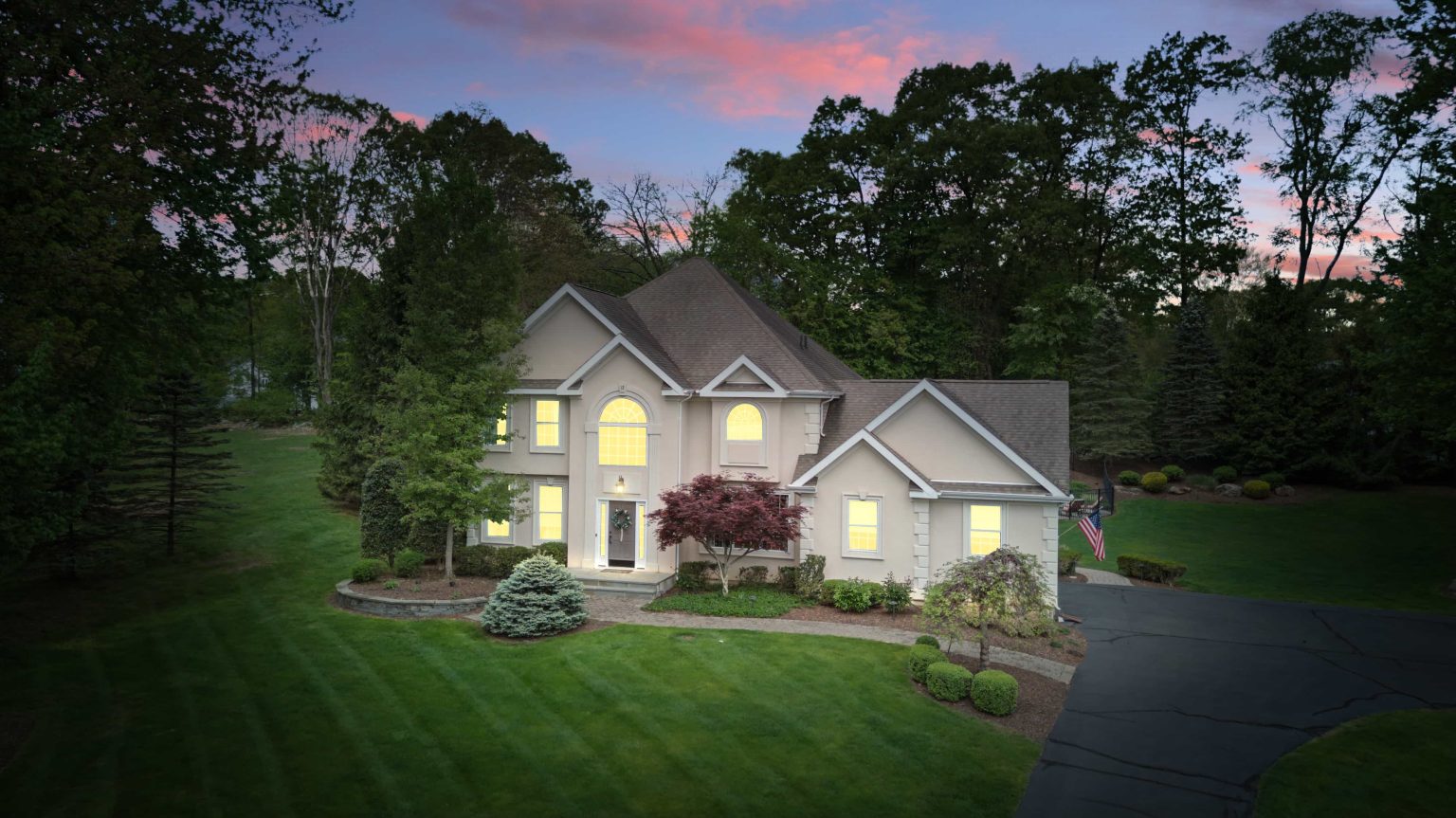 Twilight exterior of a two-story home with illuminated windows