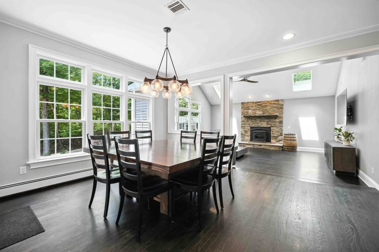 Bright dining room opening to a living room with a stone fireplace