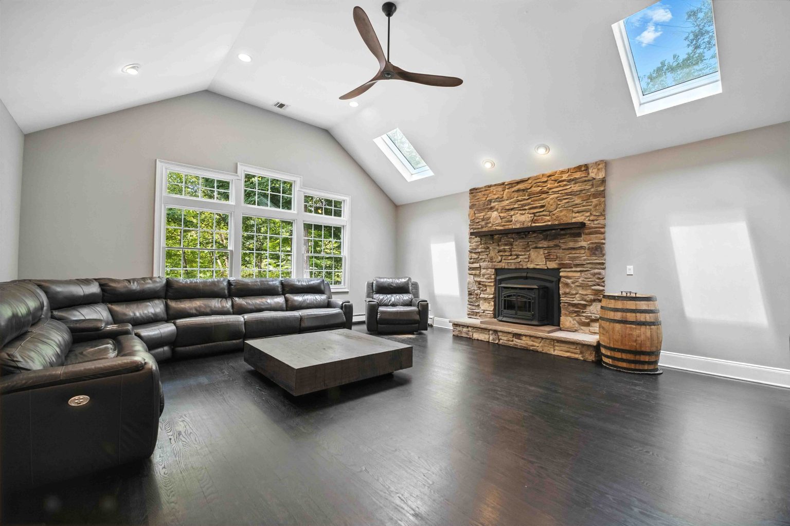 Living room with a stone fireplace, vaulted ceiling and large windows