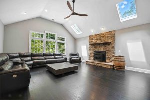 Living room with a stone fireplace, vaulted ceiling and large windows