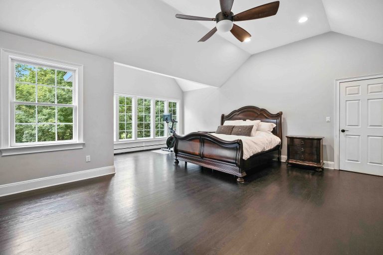 Bedroom with a dark wood bed, hardwood floors and large windows